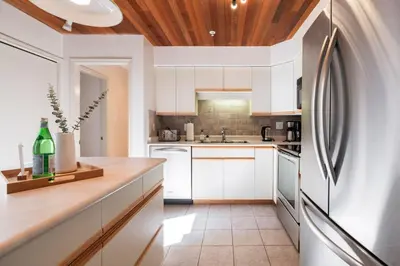 a kitchen with white cabinets and a wooden ceiling at Foxglove by Outpost Whistler in Whistler