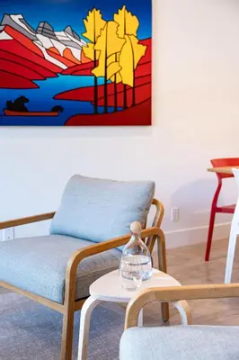 a living room with a chair and a painting on the wall at Hygge Haus by Revelstoke Vacations in Revelstoke