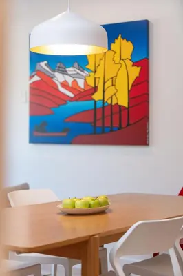 a dining room table with a painting on the wall at Hygge Haus by Revelstoke Vacations in Revelstoke