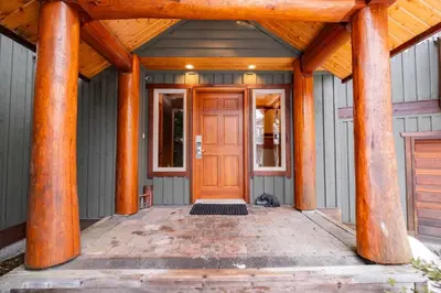 a front door of a house with wooden columns at Spruce Grove Chalet by Outpost Whistler in Whistler