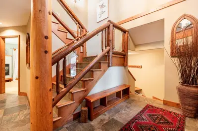 a wooden staircase in a home with a rug at Spruce Grove Chalet by Outpost Whistler in Whistler