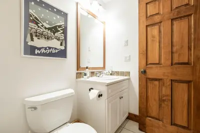 a bathroom with a toilet and a sink and a mirror at Spruce Grove Chalet by Outpost Whistler in Whistler