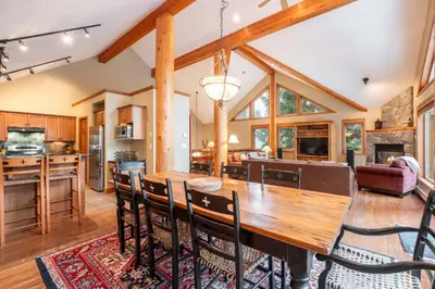 an open kitchen and dining room with a wooden table and chairs at Spruce Grove Chalet by Outpost Whistler in Whistler