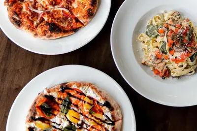 a table with three plates of food and a bowl of pasta at DoubleTree by Hilton Hotel & Suites Victoria in Victoria