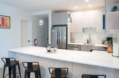 a kitchen with a white counter top and chairs at Revytalise - Cozy 3 Bedroom Condo in Revelstoke