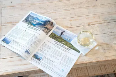 a magazine sitting on a table with a glass of wine at Revytalise - Cozy 3 Bedroom Condo in Revelstoke