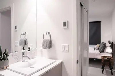 a white bathroom with a sink and a bed at Revytalise - Cozy 3 Bedroom Condo in Revelstoke