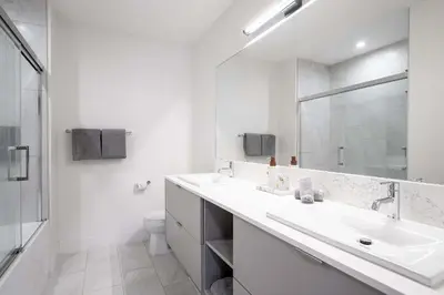 a white bathroom with a sink and a mirror at Revytalise - Cozy 3 Bedroom Condo in Revelstoke