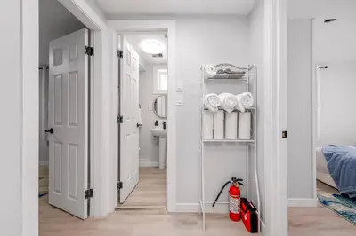 a white hallway with a bathroom with a fire extinguisher at CenterStreet-Cozy 2bedroomSuite in Calgary