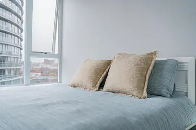 a bed with two pillows in a room with a window at Near BC Place & SkyTrain Access & Free Parking in Vancouver