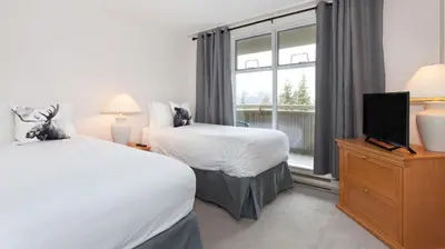 a hotel room with two beds and a window at Woodrun Lodge 517 | Large Ski-In Ski-Out Condo by Upper Village w/ Mountain Views & Shared Hot Tub in Whistler