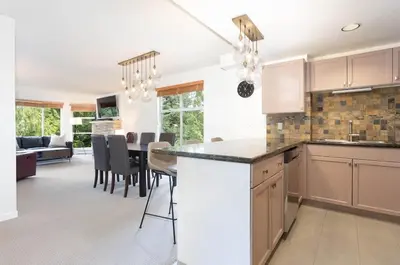 a kitchen and living room with a table and chairs at Woodrun Lodge 417 | Ski-In Ski-Out, Pool, Hot Tub, Free Parking in Whistler