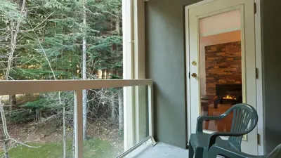 a balcony with a view of a fireplace and a chair at Woodrun Lodge 414 | Cozy Ski-In Ski-Out Condo w/ Shared Hot Tub, Pool, Fireplace, & Parking in Whistler