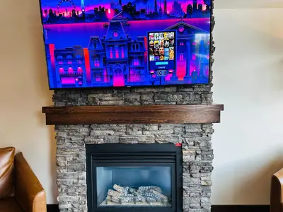 a flat screen tv hanging over a fireplace at Canmore Mountain Retreat - Heated Pool & Hot-tub in Canmore