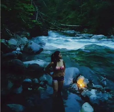 a woman standing in the water near a river at Romantic Off-Grid Cabin by Glacier lake in Pemberton