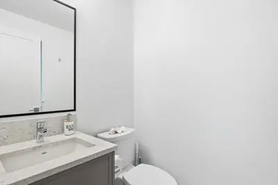 a bathroom with a sink and a toilet and a mirror at Seas The Day Saratoga at THE BEACH HOUSE in Campbell River