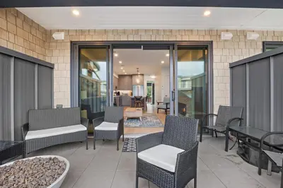 a patio with chairs and tables and glass doors at Seas The Day Saratoga at THE BEACH HOUSE in Campbell River
