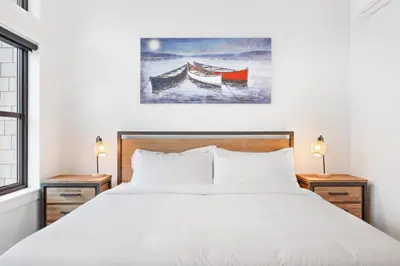 a bedroom with a bed and a boat on the water at Seas The Day Saratoga at THE BEACH HOUSE in Campbell River