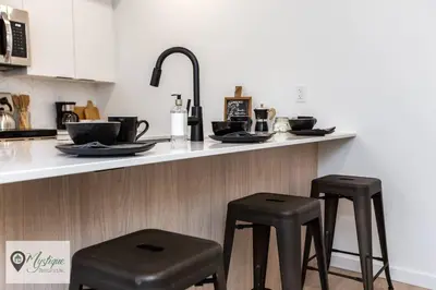 a kitchen with two black stools at a counter at Modern Suite King Bed Near Whyte Ave and U of A WIFI in Edmonton