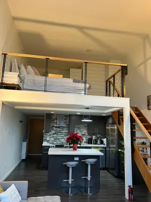 a loft conversion of a house with a bed and stools at Modern top-floor 1-bedroom loft with free parking in Vancouver