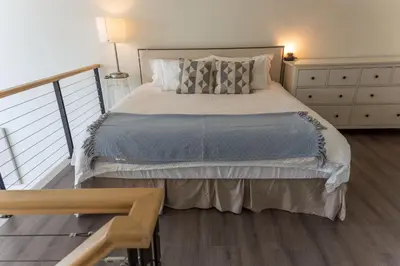 a bedroom with a large bed and a dresser at Modern top-floor 1-bedroom loft with free parking in Vancouver