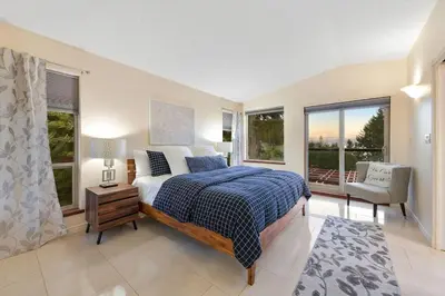 a bedroom with a large bed and windows at Dolphin House by EMR Vacation Rentals in Nanoose Bay