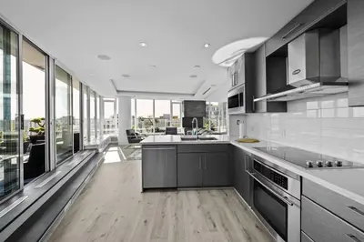 a kitchen with stainless steel appliances and large windows at Skyline Hideaway in Vancouver