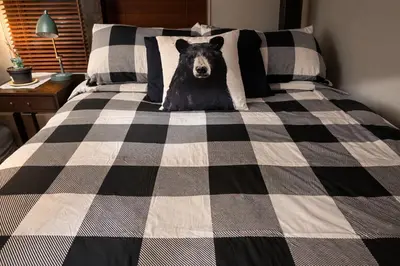 a bear is sitting on a black and white checkered bed at Summit View Alpine Retreat in Radium Hot Springs