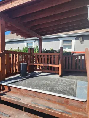 a wooden pergola with a bench on a deck at Campbell River Lodge in Campbell River