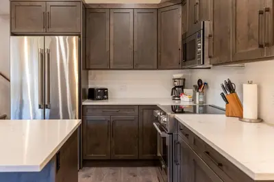 a kitchen with wooden cabinets and a stainless steel refrigerator at Polar Peak Lodges by Fernie Central Reservations in Fernie