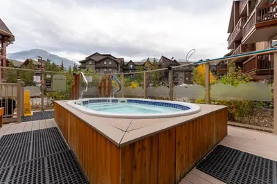a jacuzzi tub on a patio with a building at Romantic Mountain Escape - Hot Tubs & Private Balcony! managed by Little Sister Getaways in Canmore