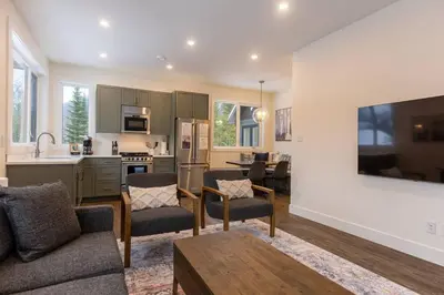a living room with a couch and a kitchen at Powder House Chalet by Fernie Central Reservations in Fernie