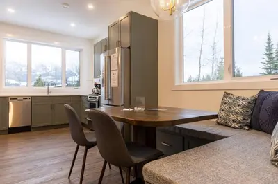 a kitchen and living room with a wooden table and chairs at Powder House Chalet by Fernie Central Reservations in Fernie