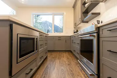a large kitchen with white cabinets and a large window at Powder House Chalet by Fernie Central Reservations in Fernie