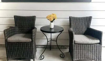two wicker chairs and a table with a vase of flowers at Blissful Stay in Surrey in Surrey