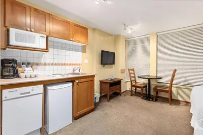 a kitchen with a sink and a table with a microwave at Cascade Lodge with front desk check in services, ski valet service, boot and glove dryer, 2 hot tubs, year round heated pool, gym, sauna, change rooms & showers, WIFI, cable TV in Whistler
