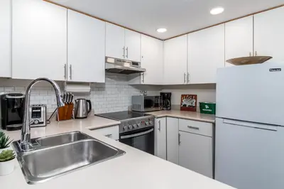 a kitchen with white cabinets and a stainless steel sink at Creekside Slopeside 1BR with pool, hot tub, BBQ in Whistler