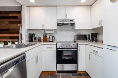 a kitchen with white cabinets and stainless steel appliances at Creekside Slopeside 1BR with pool, hot tub, BBQ in Whistler