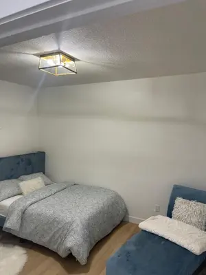 a bedroom with a bed and a blue couch at Stylish 2 Bedroom suite in SW Edmonton close to Windermere and Edmonton International Airport in Edmonton