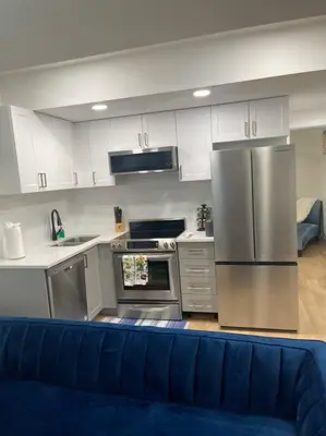 a kitchen with stainless steel appliances and a blue couch at Stylish 2 Bedroom suite in SW Edmonton close to Windermere and Edmonton International Airport in Edmonton