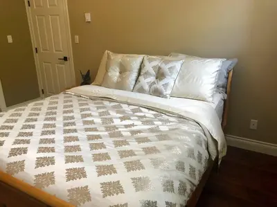 a bed with a white comforter and pillows at Upscale Character Home with Luxurious Amenities in Victoria