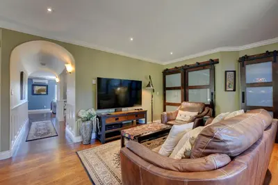 a living room with a leather couch and a television at Character Stay across Swan Lake Nature Sanctuary in Victoria