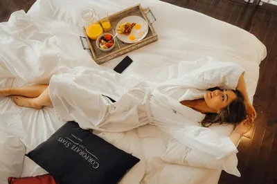 a woman laying on a bed with a tray of food at Hendrix Luxury Apartments by Corporate Stays in Edmonton