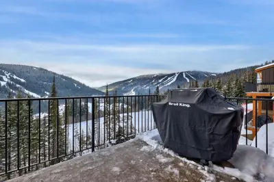 a trash can sitting on top of a balcony with mountains at Powder Heights #18 townhouse in Sun Peaks