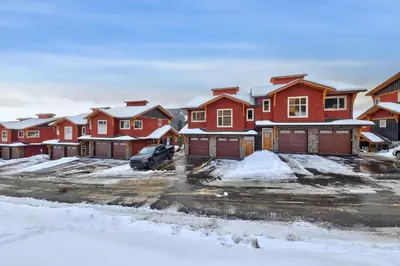 a row of houses in a parking lot with snow at Powder Heights #18 townhouse in Sun Peaks