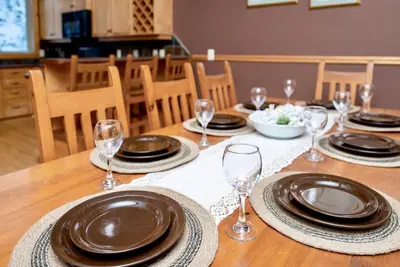 a wooden table with plates and wine glasses on it at Eagle Ridge Pet-Friendly Chalet in Big White