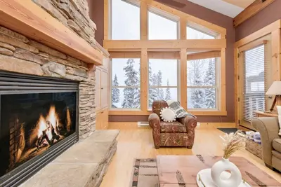 a living room with a fireplace and a chair at Eagle Ridge Pet-Friendly Chalet in Big White