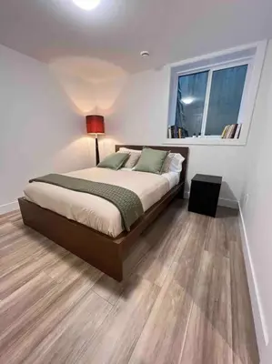 a bedroom with a bed and a window and a lamp at Grand Boulevard Basement Suite in North Vancouver