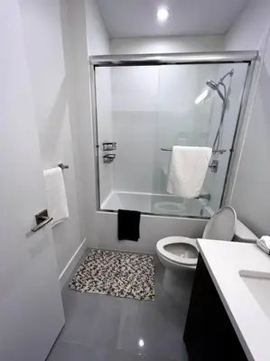 a white bathroom with a shower and a toilet at Grand Boulevard Basement Suite in North Vancouver