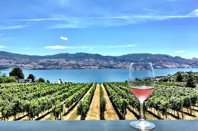 a glass of wine sitting on a table next to a vineyard at Lakeviews, big yard/deck, minutes to Silver Star/Golf/Wineries. in Vernon